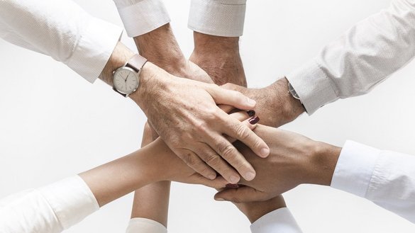 Acht Hände die sich in der Mitte berühren