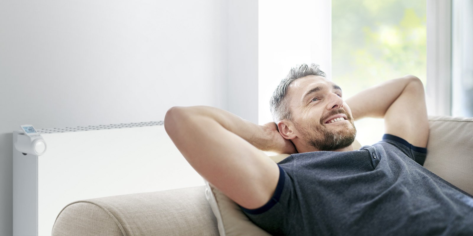 Ein Mann der auf dem Sofa liegt mit den Haenden hinterm Kopf 