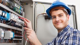 Ein junger Elektroniker überprüft einen Verteilerkasten 